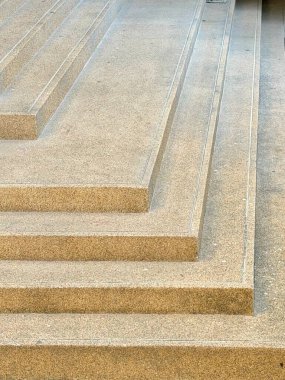 Çağdaş beton bir merdivenin yakın çekim görüntüsü. Açığa çıkmış toplu bir bitiriş var. Geometrik adımlar ve paralel çizgiler, mimari ve kentsel tasarım temaları için ideal soyut, dokulu bir arkaplan oluşturur.