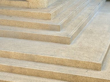 Açık hava bej beton basamaklarının yüksek açılı yakın çekimi, pürüzlü, açıkta kalan toplam doku ve ince beyaz kayma önleyici şeritler, modern geometrik desenler yaratıyor..