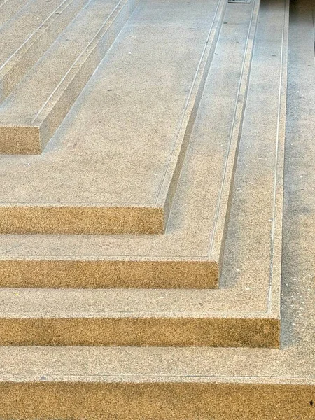 Çağdaş beton bir merdivenin yakın çekim görüntüsü. Açığa çıkmış toplu bir bitiriş var. Geometrik adımlar ve paralel çizgiler, mimari ve kentsel tasarım temaları için ideal soyut, dokulu bir arkaplan oluşturur.