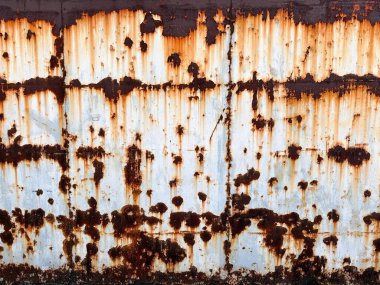 Üzerinde saat olan paslı bir duvar.