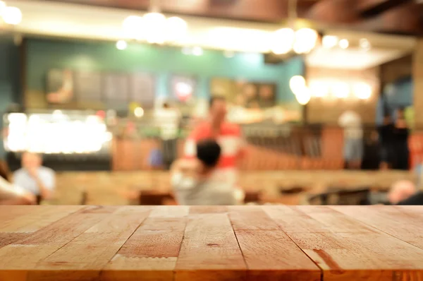 Tampo da mesa de madeira no fundo borrão do interior da cafetaria — Fotografia de Stock