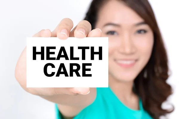 HEALTH CARE, message on the card shown by smiling woman — Stock Photo, Image