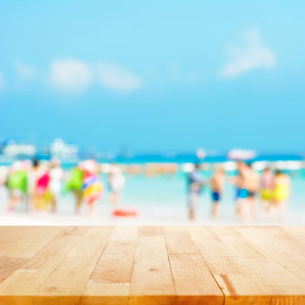 Mesa de madera con gente borrosa en la playa —  Fotos de Stock