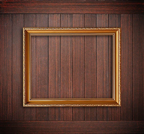 Golden picture frame on wooden wall — Stock Photo, Image