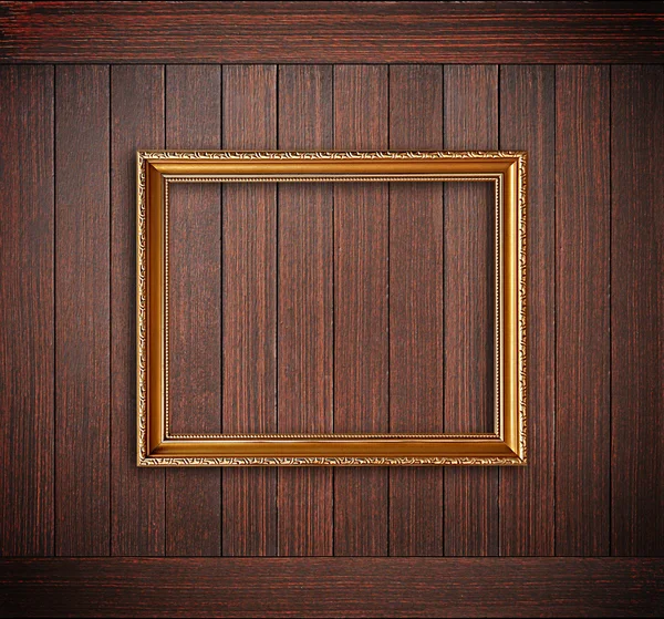 Golden picture frame on wooden wall — Stock Photo, Image