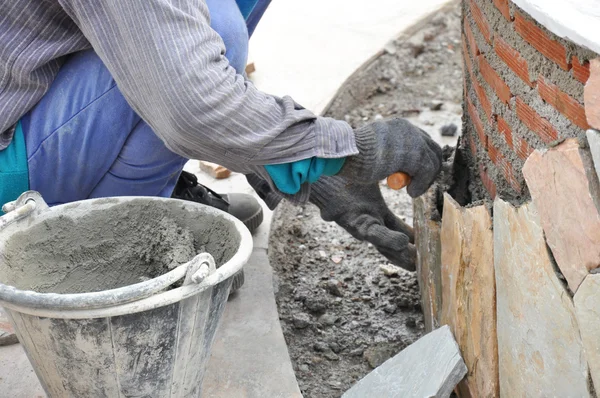 Travailleur maçon installant des dalles sur un mur de briques — Photo