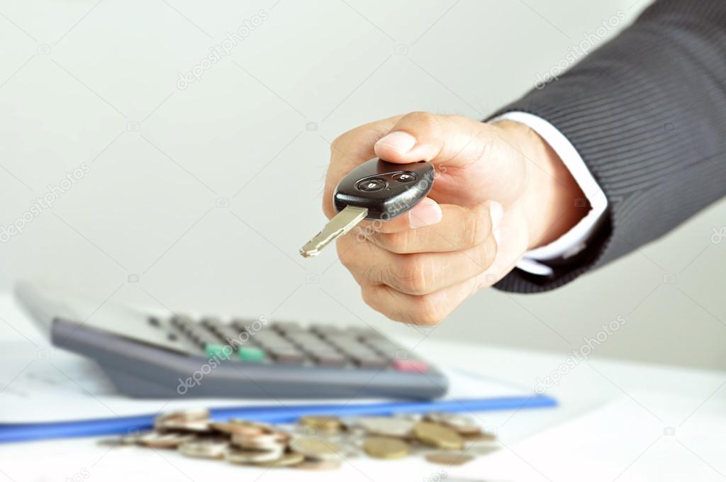 Businessman hand giving a car key - car rent, sale & pawn concepts