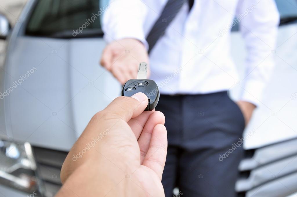 Hand giving a car key to another man