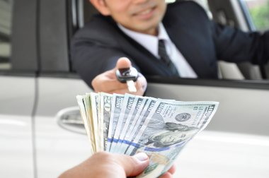 Bir araba anahtar ile para alışverişi veren işadamı