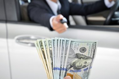 Bir araba anahtar ile para alışverişi veren işadamı