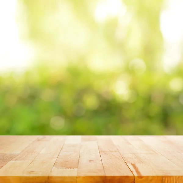 Holz Tischplatte auf verschwommenem grünen abstrakten Hintergrund — Stockfoto