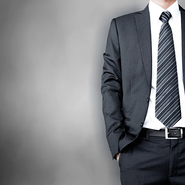 Empresario con traje y corbata de pie sobre fondo gris — Foto de Stock