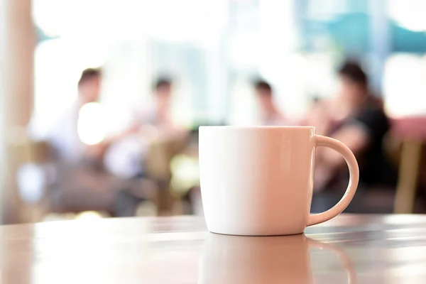 Coffee cup on the table with people in coffee shop as blur background