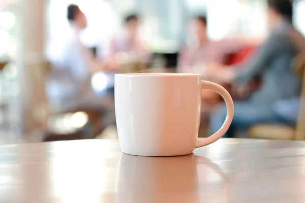 Tasse à café sur la table avec des gens dans le café comme fond flou — Photo