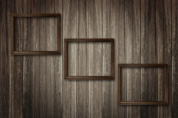 Photo frames on dark wooden wall — Stock Photo, Image