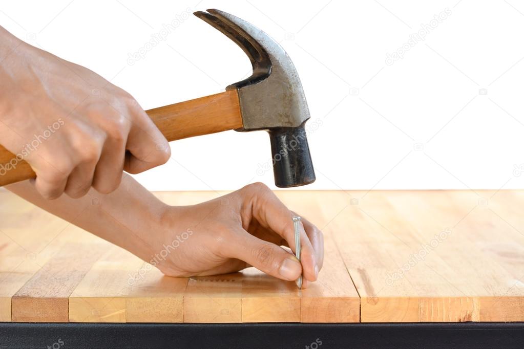 Hand hammering a nail on wood table top