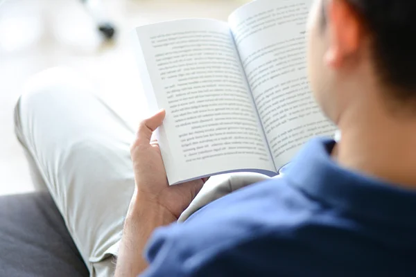 A man reading book while sitting on the couch — Stock Photo, Image