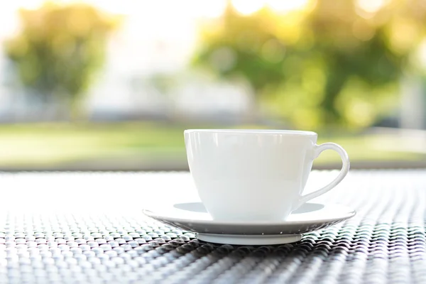 Taza de café con libro sobre fondo de la naturaleza verde borrosa — Foto de Stock