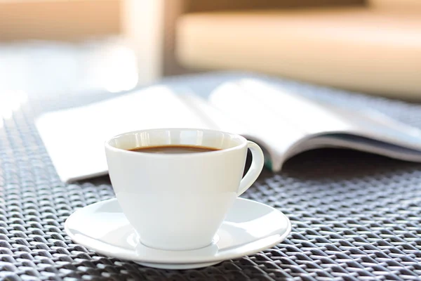 Tasse à café avec livre sur table en osier brun — Photo