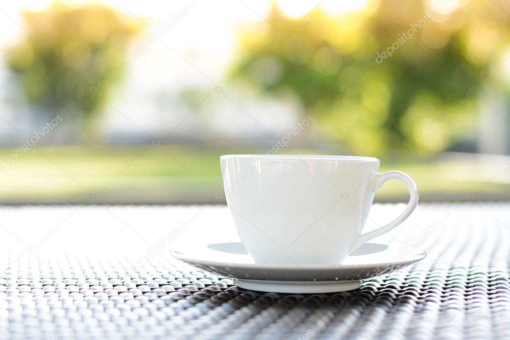 Coffee cup with book on blurred green nature background