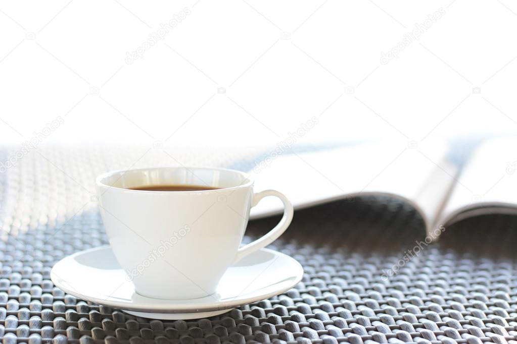 Coffee cup with book  on brown wicker table