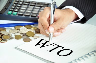 Businessman hand with pen pointing to WTO (or World Trade Organization) on the paper clipart