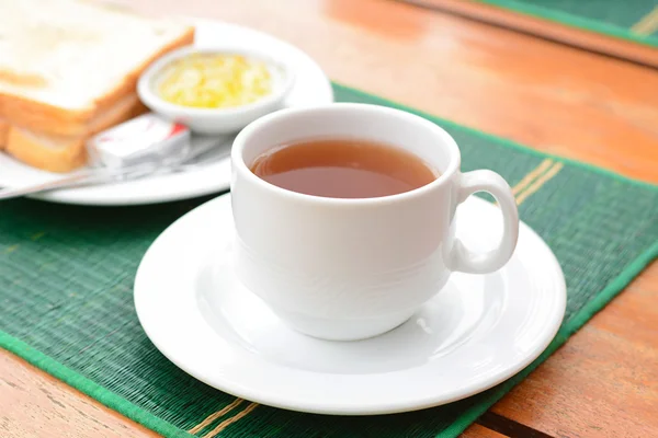 Chá quente na xícara branca com pão fatiado no tapete verde — Fotografia de Stock