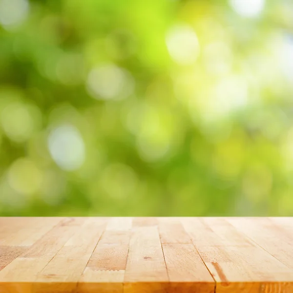 Dřevo stolu na pozadí zelených bokeh — Stock fotografie