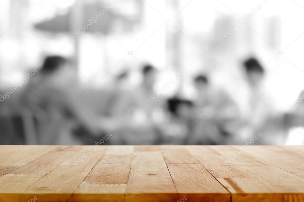 Wood table top with blurred monochrome background of people sitting in cafe