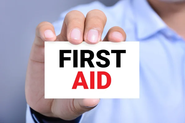 FIRST AID message on the card show by a man — Stock Photo, Image
