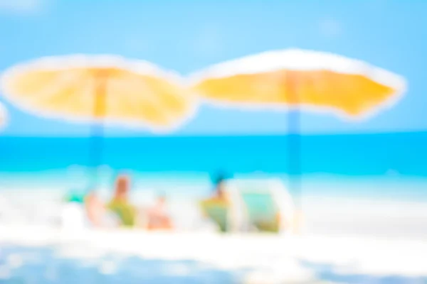 Achtergrond wazig strand met parasols en sommige mensen — Stockfoto