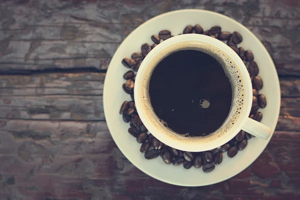 Café negro en la taza en la mesa de madera vieja (vista superior) - tono vintage —  Fotos de Stock