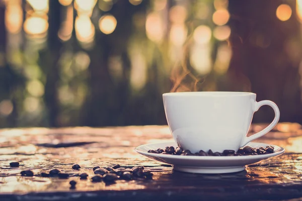 Café quente na xícara na mesa de madeira velha com borrão nat verde escuro — Fotografia de Stock