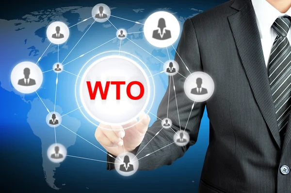 Podnikatel, ukazující na Wto (Světová obchodní organizace) přihlášení v — Stock fotografie