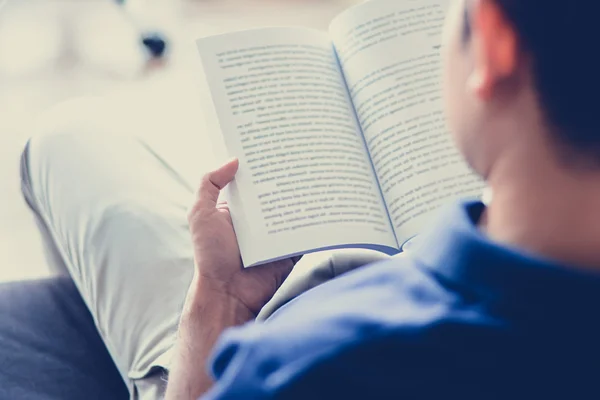 A man reading book while sitting on the couch - vintage tone — Stock Photo, Image