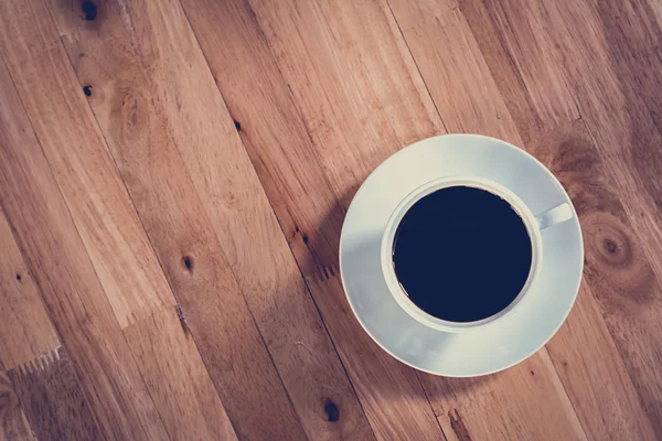 Taza de café sobre mesa de madera (vista superior) - tono vintage —  Fotos de Stock