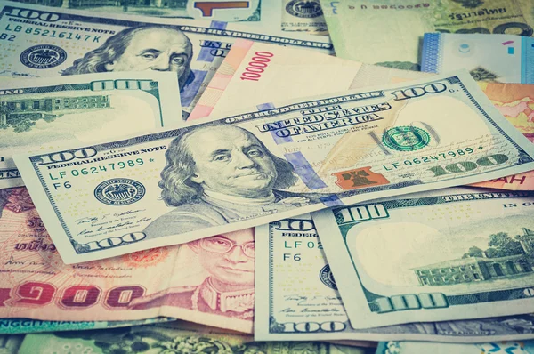 Деньги в мультивалюте с банкнотой 100 долларов США сверху - винтажный тон — стоковое фото