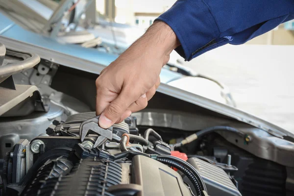 Mano mecánica con llave inglesa que fija el motor del coche — Foto de Stock