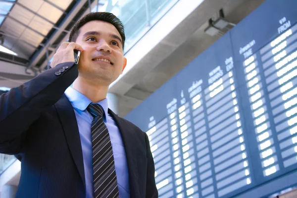 Businessman talking on cell phone inside the airport terminal wi — Stock Photo, Image