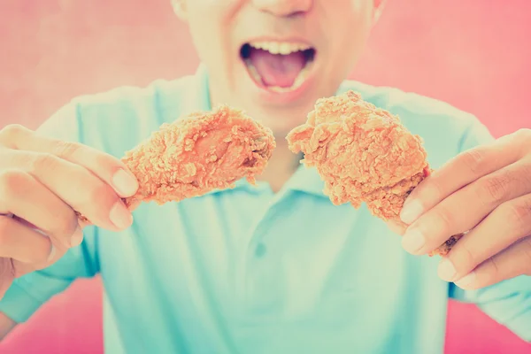 Un hombre con la boca abierta a punto de comer patas de pollo fritas o muslos - tono vintage —  Fotos de Stock