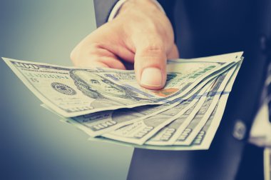 Businessman hand giving money, US dollars (USD)