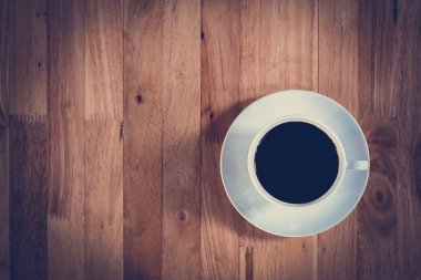 Top view of black coffee in the cup on wooden table clipart