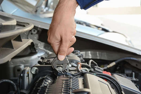 Mechanic hand holding wrench fixing car engine — Stock Photo, Image