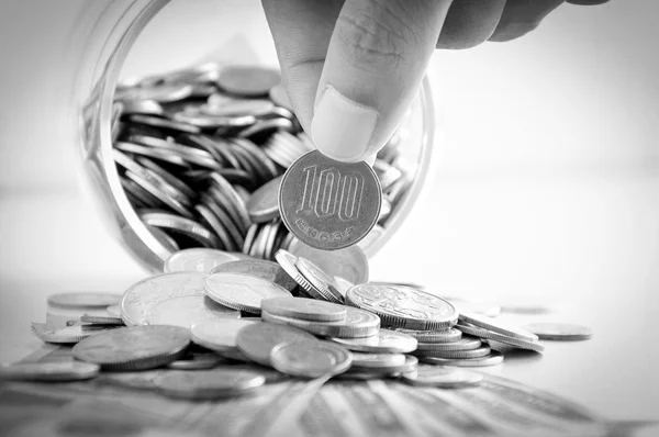 Hand picking up 100 Japanese yen (JPY) coin out of multi currency pile of coins — Stockfoto