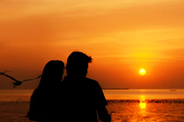 Silhueta de macho e fêmea como casal no litoral em romântico crepúsculo pôr do sol fundo — Fotografia de Stock