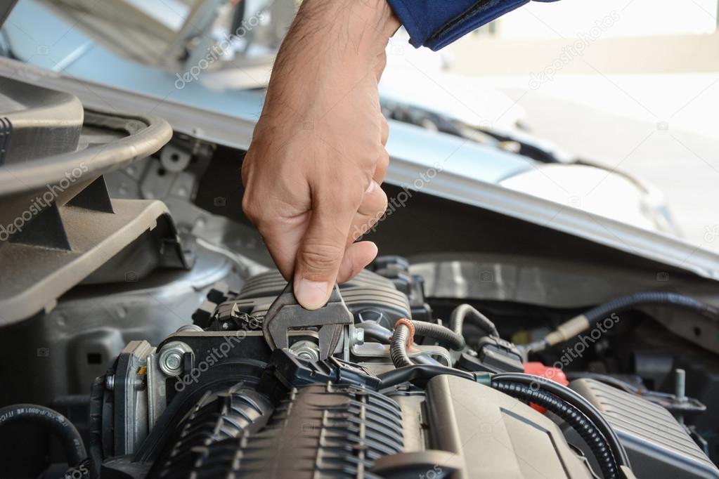 Mechanic hand holding wrench fixing car engine