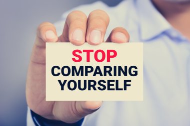 STOP COMPARING YOURSELF, message on the card shown by a man clipart