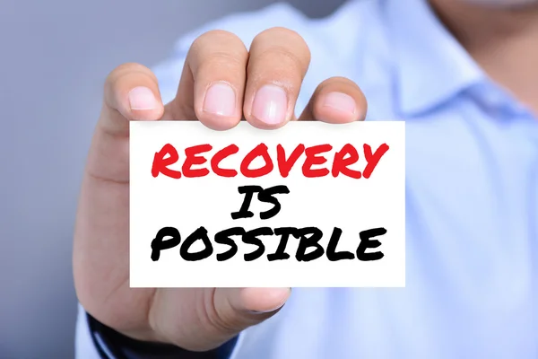 RECOVERY IS POSSIBLE, message on business card shown by a man — Stock Photo, Image