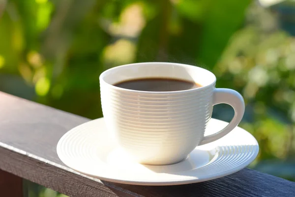 Coffee cup on wood balcony rail in blur green natural background — Stock Photo, Image