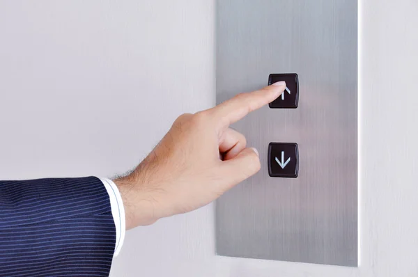 Businessman hand touching going up sign on lift control panel — Stock Photo, Image